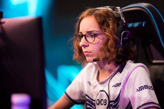 Naïma playing in the OOB team jersey, with a headset, at an esports event
